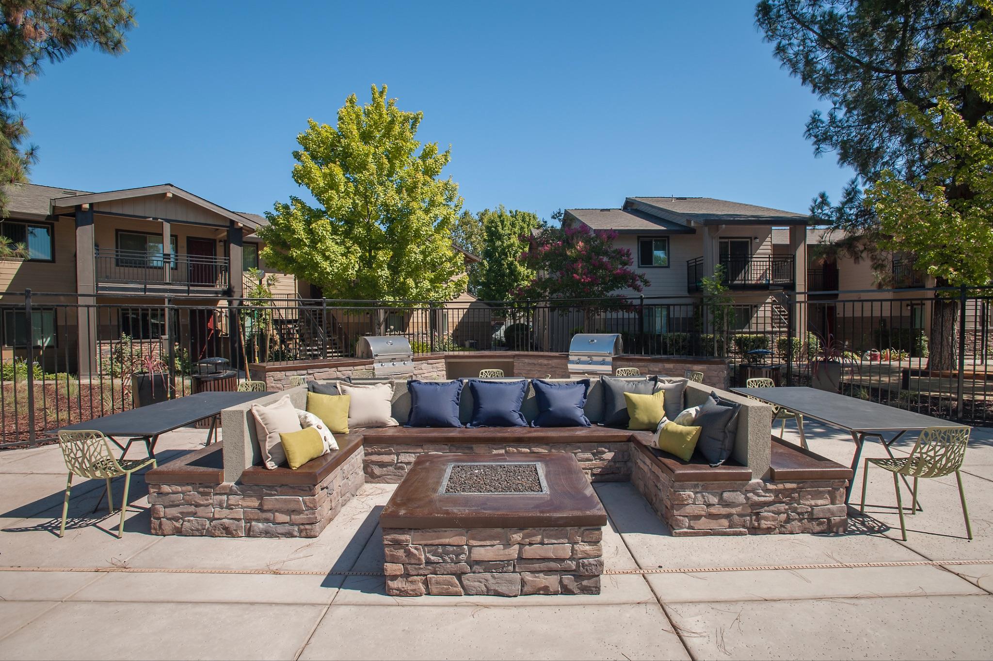Apartment community courtyard with stone fire pit and outdoor lounge seating